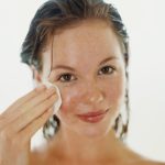 Mulher passando creme no rosto