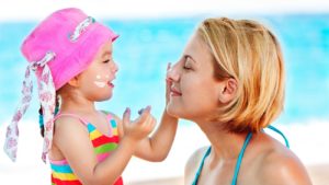 Criança passando protetor solar na mãe