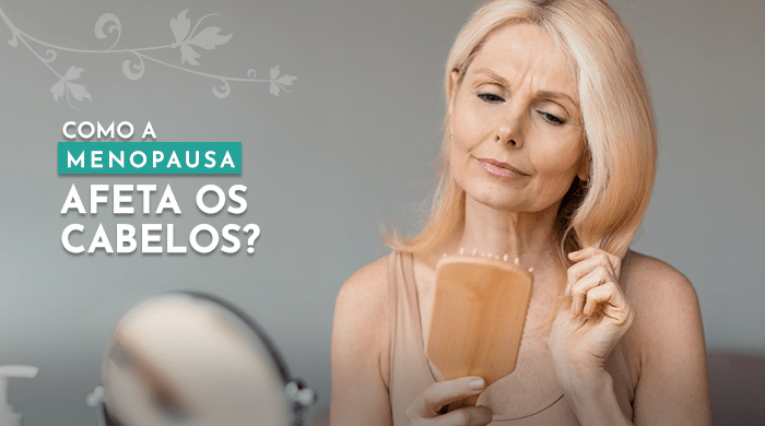 A imagem mostra um mulher loira de meia-idade olhando preocupada para uma escova de cabelo em suas mãos, refletindo os efeitos da menopausa na saúde dos cabelos.